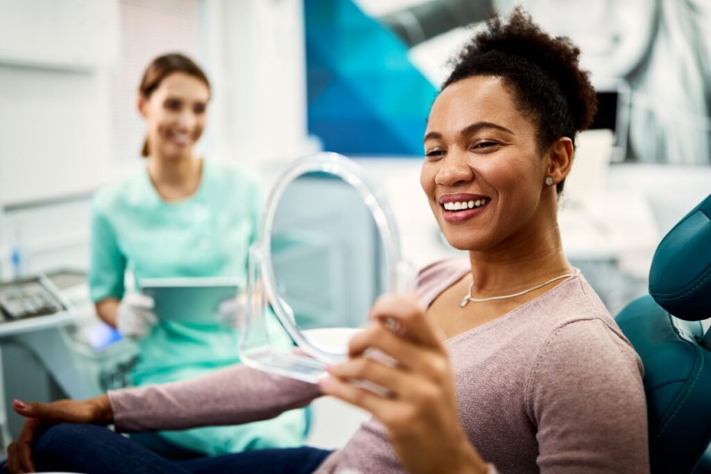 happy black woman looking her teeth in a mirror