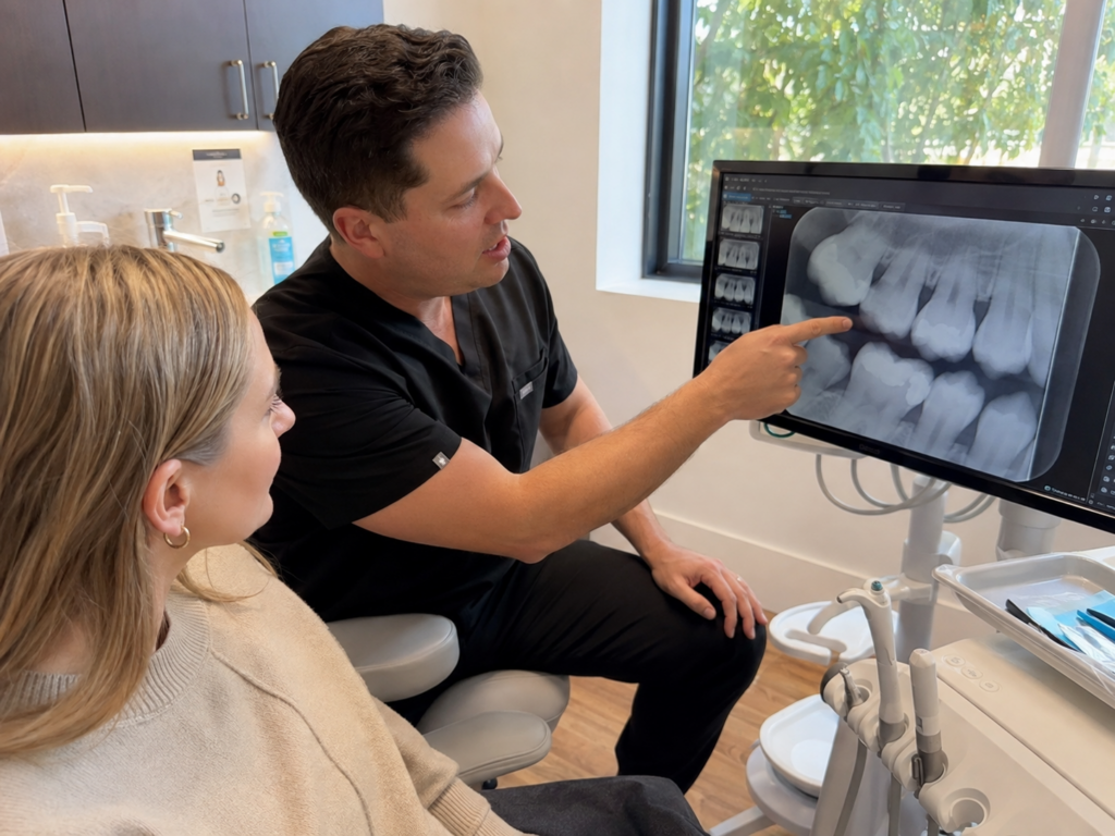 Dentist reviewing digital X-rays with a patient while explaining dental treatment priorities.